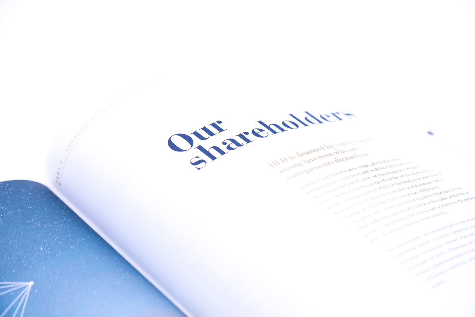 Gros plan d'un magazine ou d'un rapport ouvert montrant le titre Nos actionnaires en caractères bleus gras, avec un texte flou en dessous et un graphique bleu visible sur le côté gauche de la page.