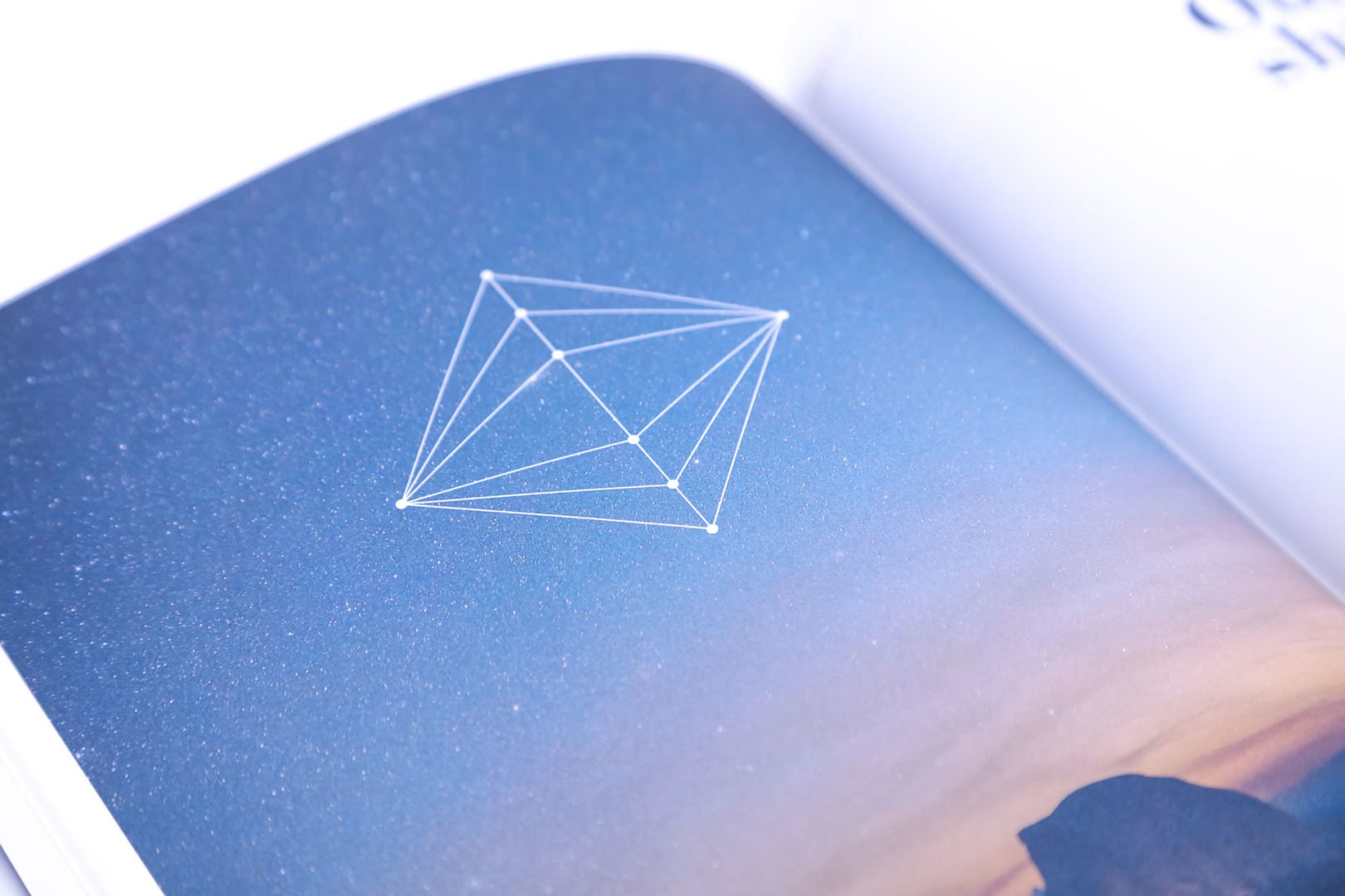 Un livre ouvert affiche une forme géométrique filaire avec des points connectés, sur un fond de ciel étoilé qui se transforme en un doux dégradé à l'horizon.