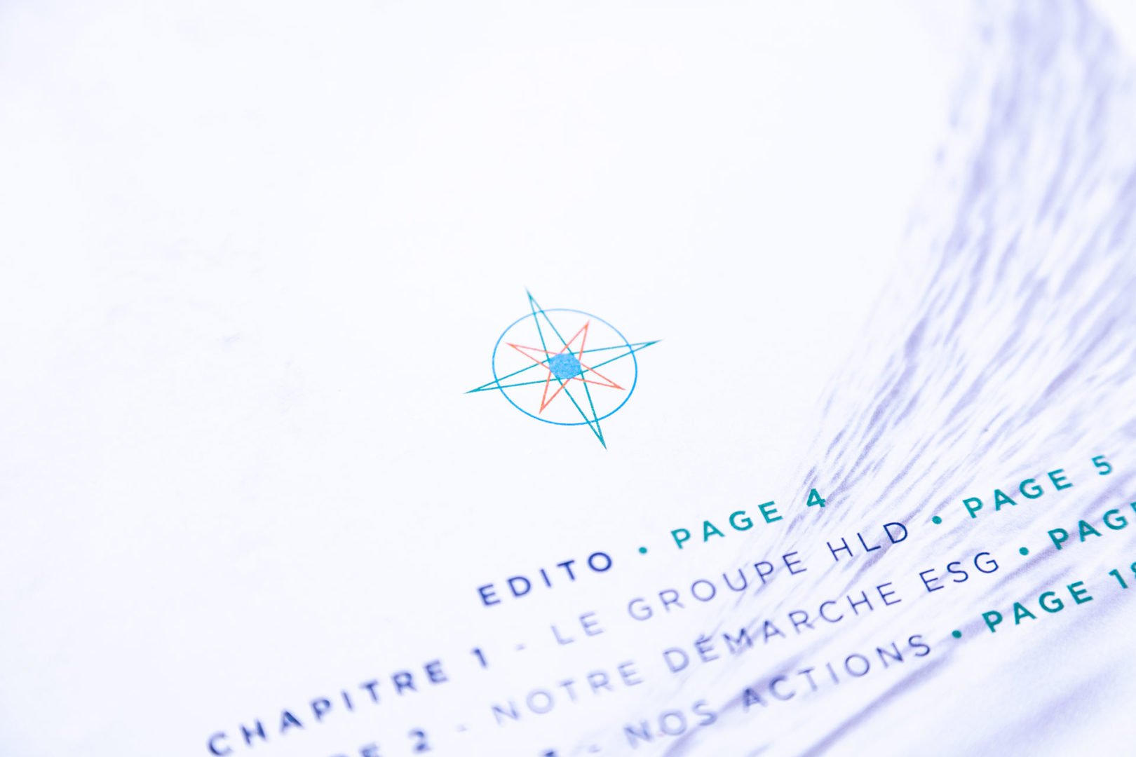 Gros plan d'une page imprimée montrant un graphique de boussole sarcelle et orange au-dessus d'une table des matières avec le texte français et les numéros de page surlignés en vert.