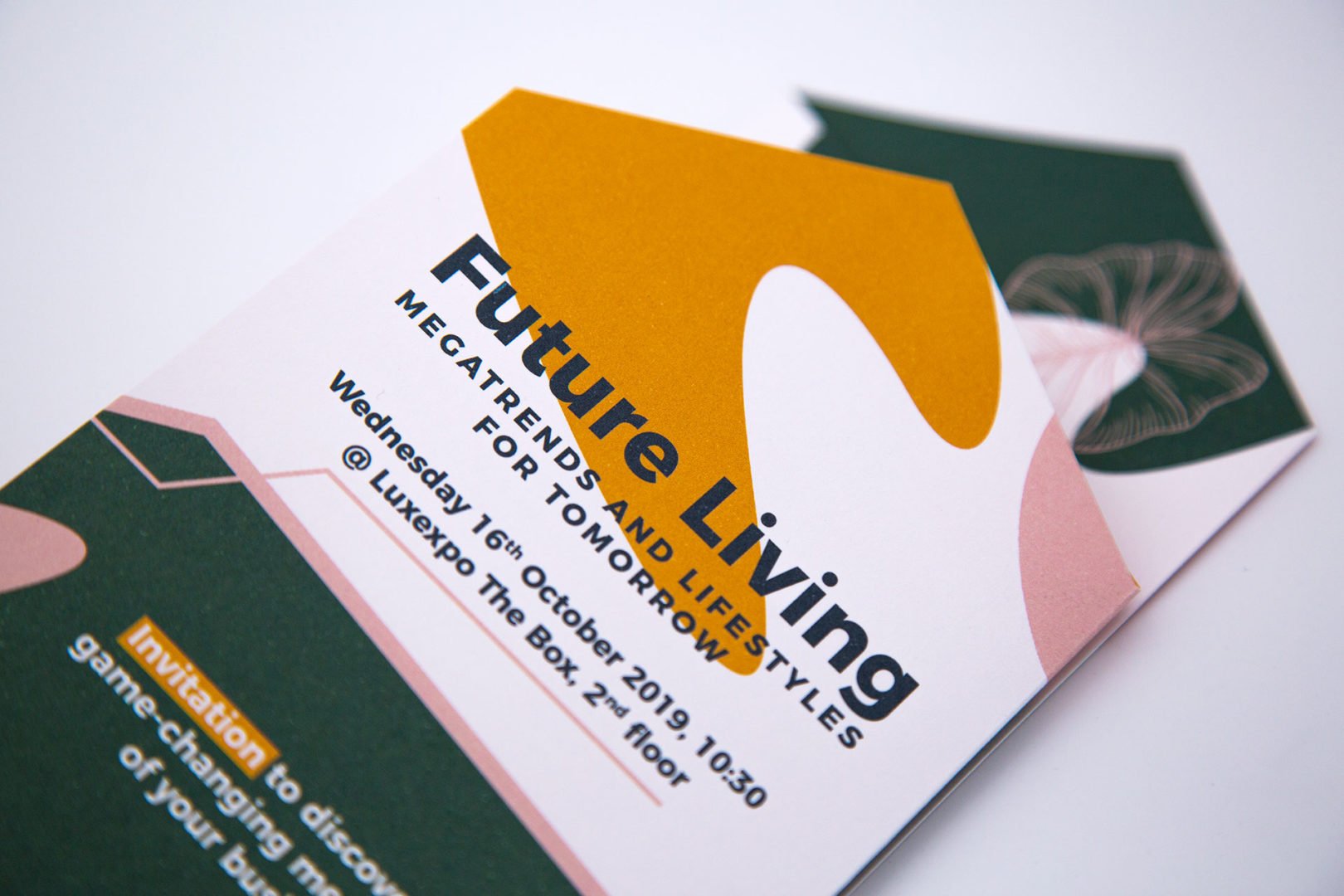 Gros plan sur une carte d'invitation moderne et colorée intitulée Future Living : Megatrends and Lifestyles for Tomorrow, avec les détails de l'événement du mercredi 16 octobre 2019 à Luxexpo, avec des formes abstraites et du texte en gras.