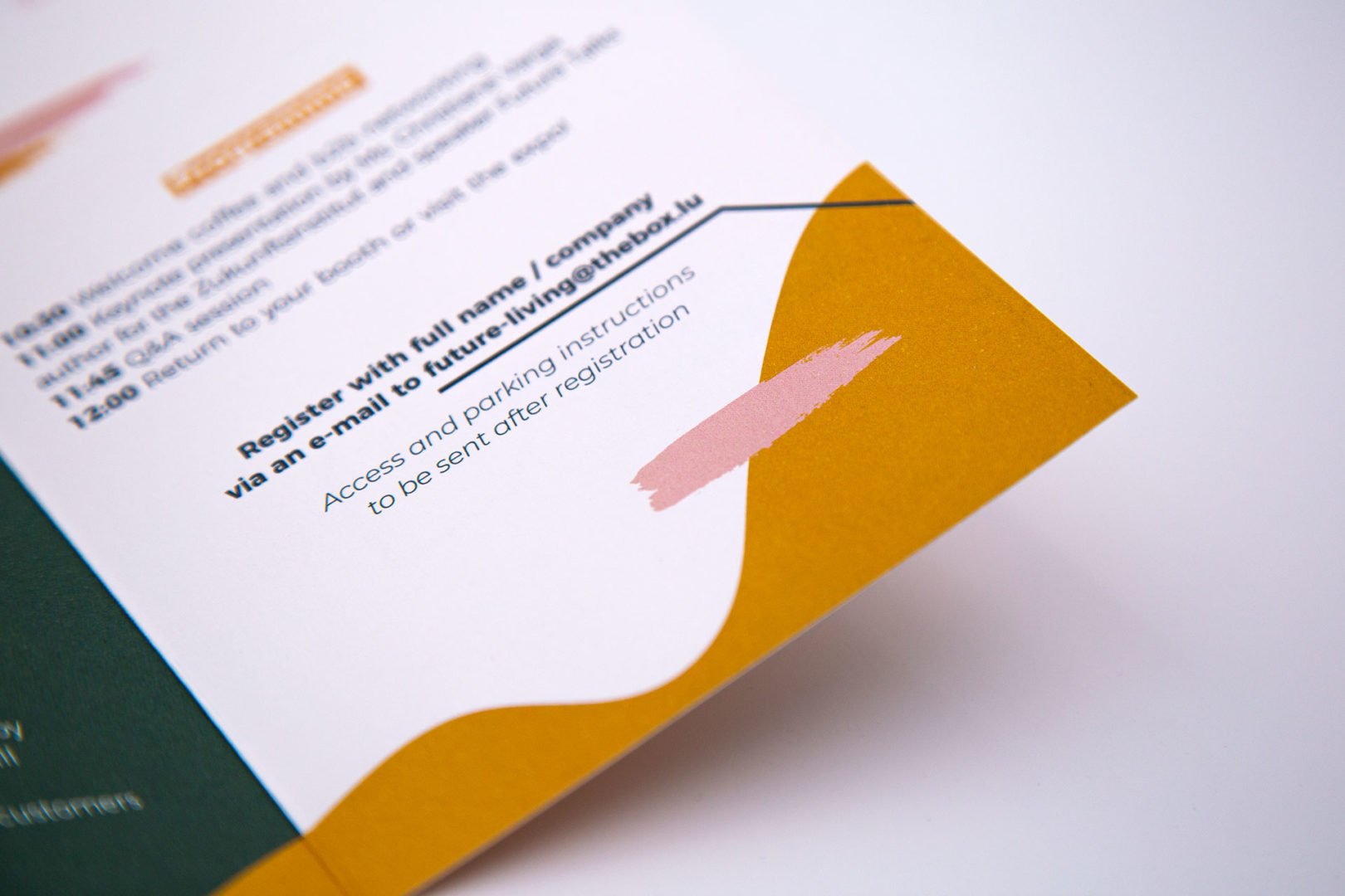 Gros plan d'un coin de brochure présentant des éléments graphiques abstraits jaunes et roses, avec un texte sur l'inscription, l'accès et les instructions de stationnement sur fond blanc.