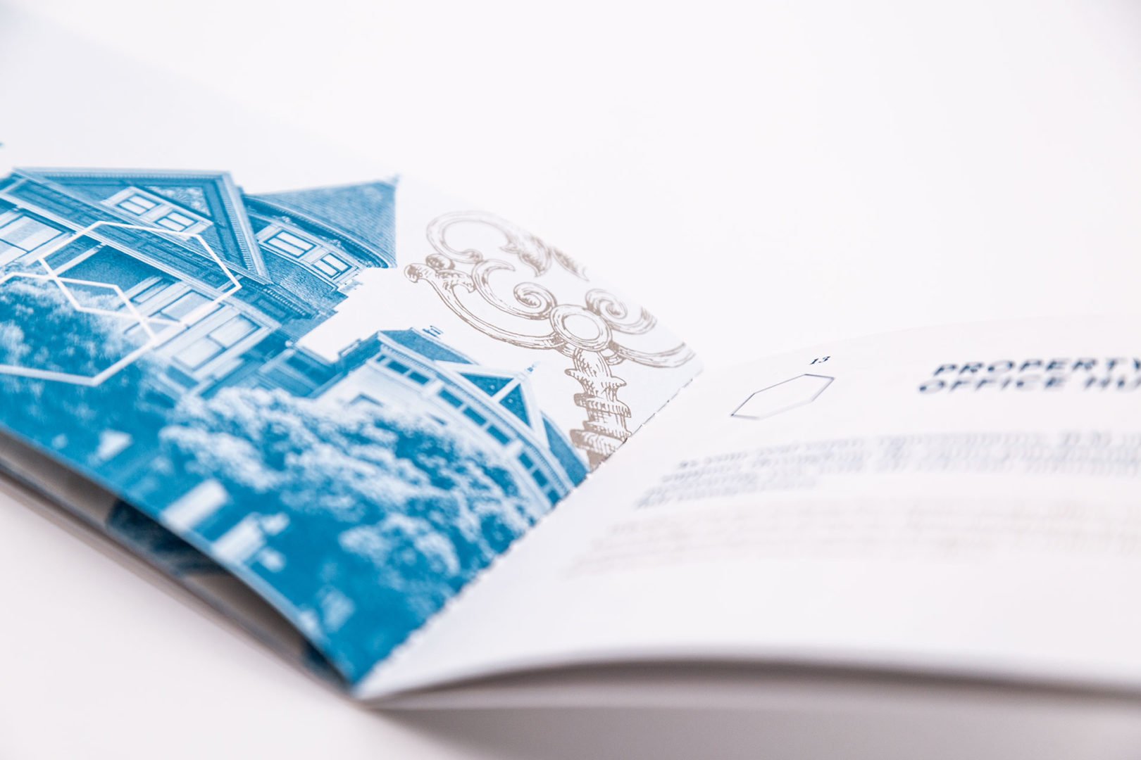 Gros plan d'une brochure ouverte présentant une image en tons bleus d'une maison et d'un lampadaire décoratif, avec un texte imprimé partiellement visible sur le côté droit.