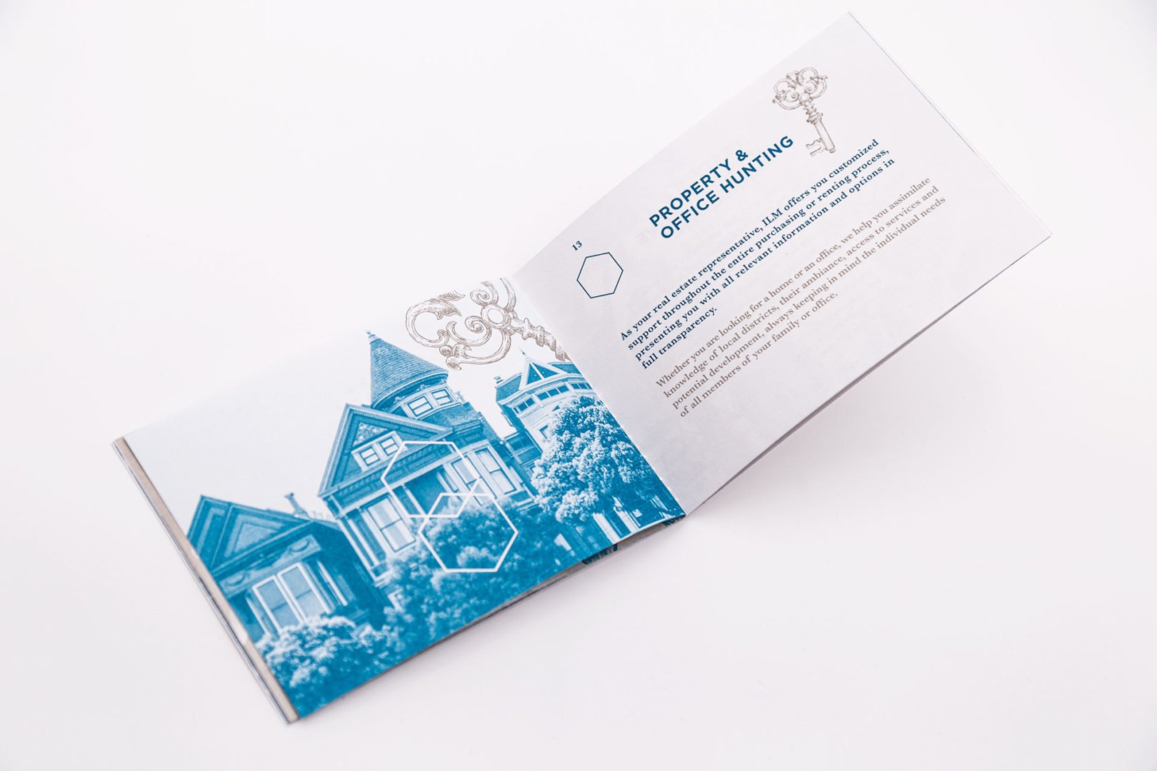 Un livret ouvert sur une surface blanche présente une image de maisons teintée en bleu sur la page de gauche et un texte sur la recherche de propriétés ou de bureaux sur la page de droite, agrémenté d'un graphique clé.