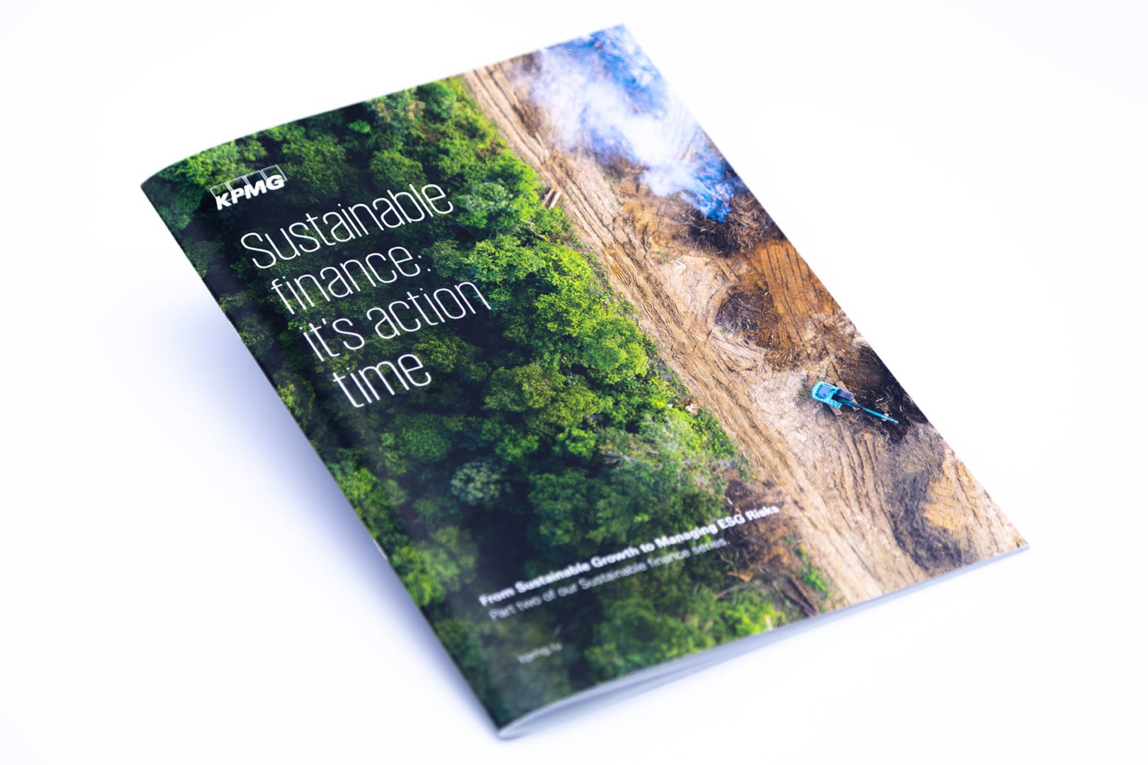 Vue oblique d'un rapport de KPMG intitulé Sustainable finance : its action time avec une photo de couverture montrant une forêt à côté d'une zone déboisée avec des engins de chantier.