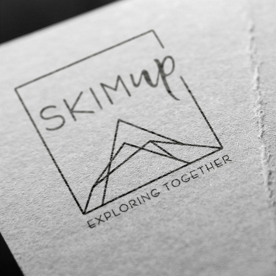 Gros plan d'un logo comportant le mot SKIM UP au-dessus d'une ligne de montagne simple, le tout entouré d'un carré. En dessous, le titre d'appel se lit EXPLORER ENSEMBLE. Le dessin est imprimé sur du papier texturé.