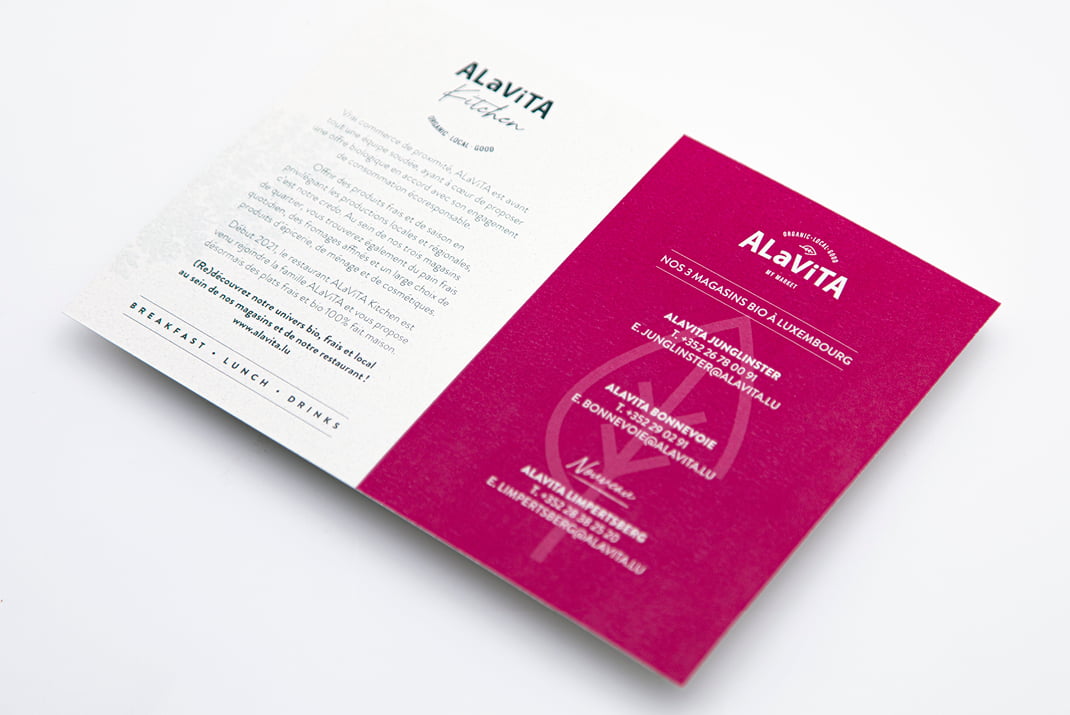 Menu de restaurant plié pour ALaViTA, avec sur le côté gauche un message de bienvenue sur fond blanc, et sur le côté droit la liste des plats du menu sur fond magenta.