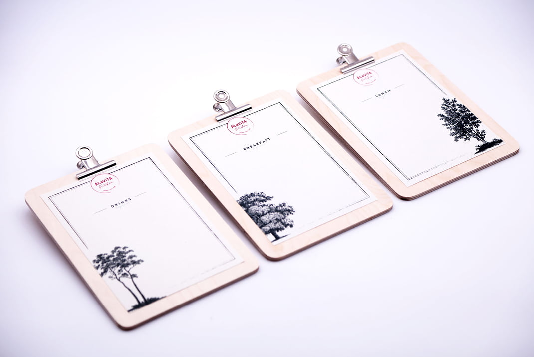 Trois planchettes à pince en bois avec des feuilles de papier minimalistes sont disposées côte à côte. Chaque feuille présente une illustration d'arbre différente et une section pour l'écriture, étiquetée Boisson, Petit-déjeuner et Déjeuner en haut.