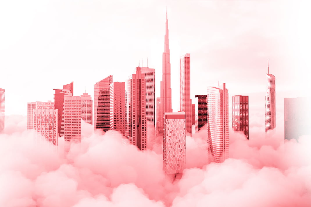 La ligne d'horizon d'une ville avec de grands gratte-ciel modernes s'élève au-dessus de nuages denses, avec des bâtiments teintés dans des nuances de rose et de rouge sur un ciel doux.