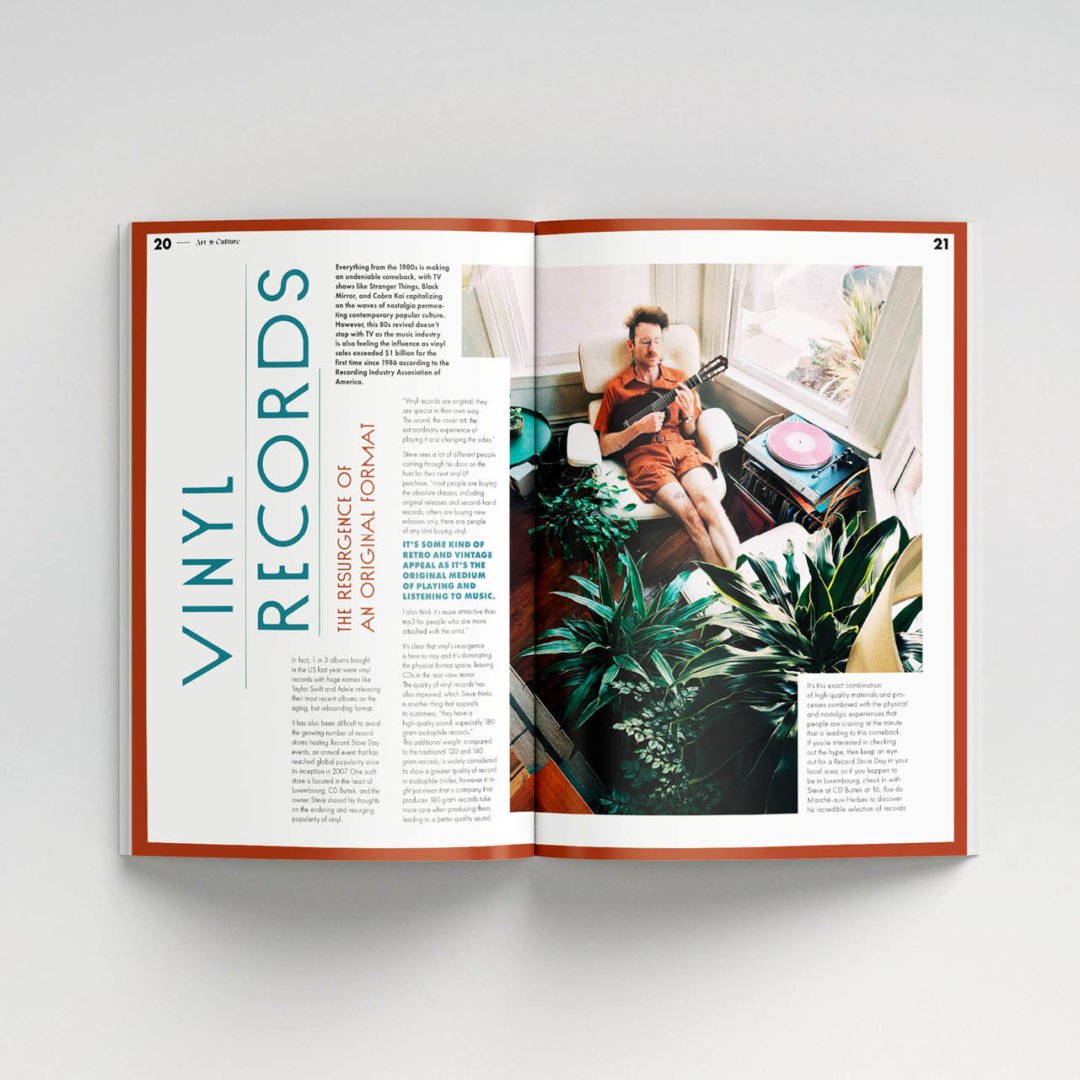 Un magazine ouvert présente un article sur le style de vie et les disques vinyles. La page de droite montre un homme parmi des plantes dans une pièce ensoleillée, tenant une guitare près de sa platine. Sur la page de gauche, on peut lire verticalement et en gras 