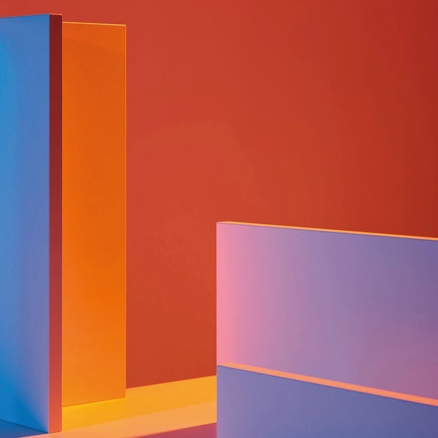 Des formes géométriques aux arêtes vives sont éclairées par des lumières colorées, créant des dégradés de bleu, d'orange, de rose et de violet sur un fond rouge vif. La scène est abstraite et minimaliste.