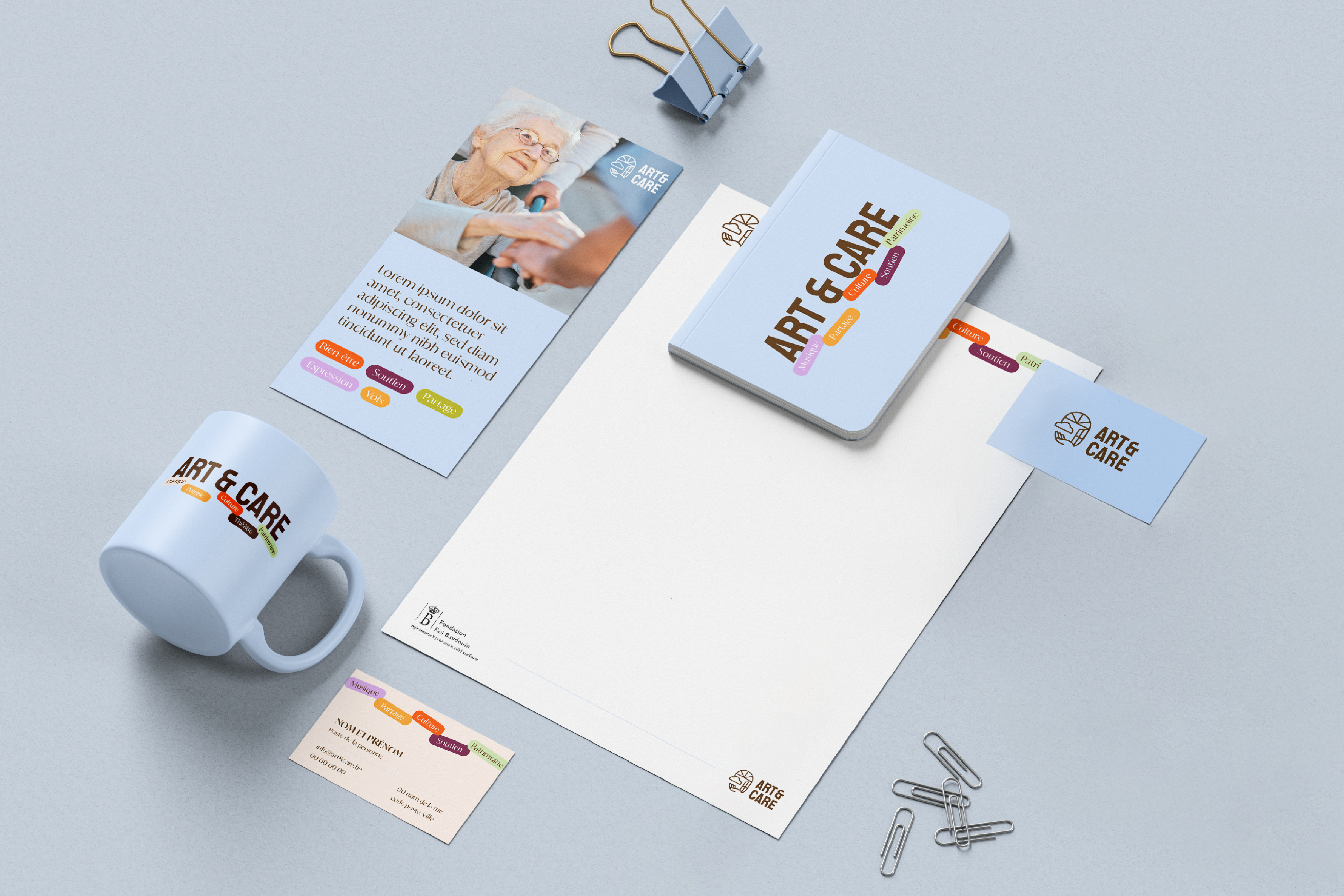 Une présentation à plat d'articles de bureau de marque, comprenant un mug, un flyer, un carnet, du papier à en-tête, une carte de visite, une pince à classeur, des trombones et un stylo, tous arborant le logo ART & CARE et des éléments de design colorés.