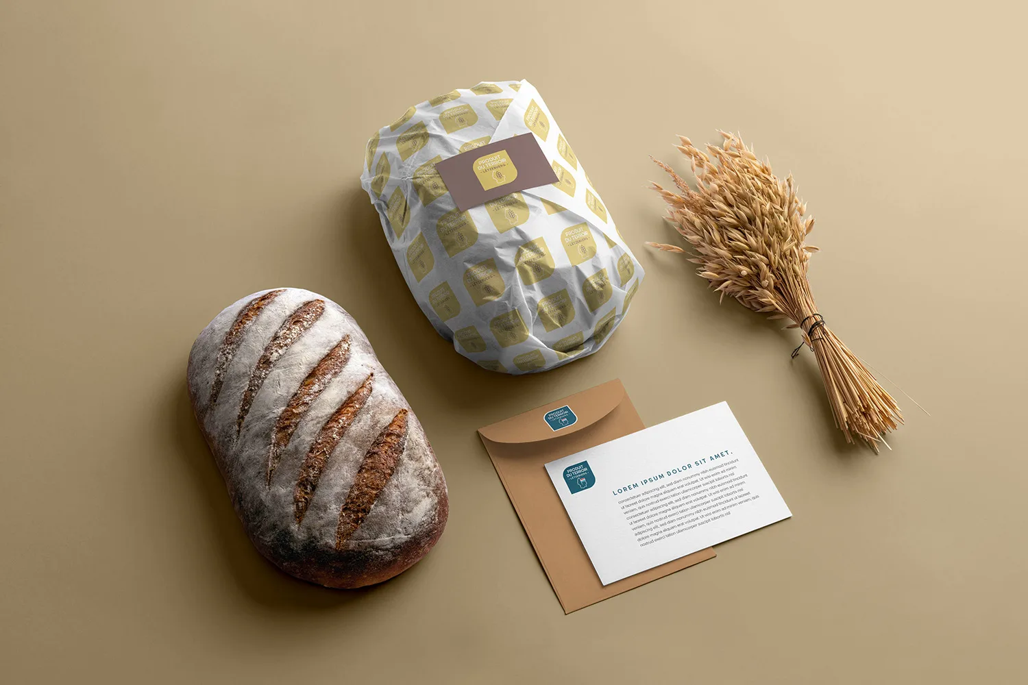 Une miche de pain croustillant, un pain emballé avec une étiquette, une botte de blé sec et une carte avec une enveloppe sont disposés sur un fond beige.