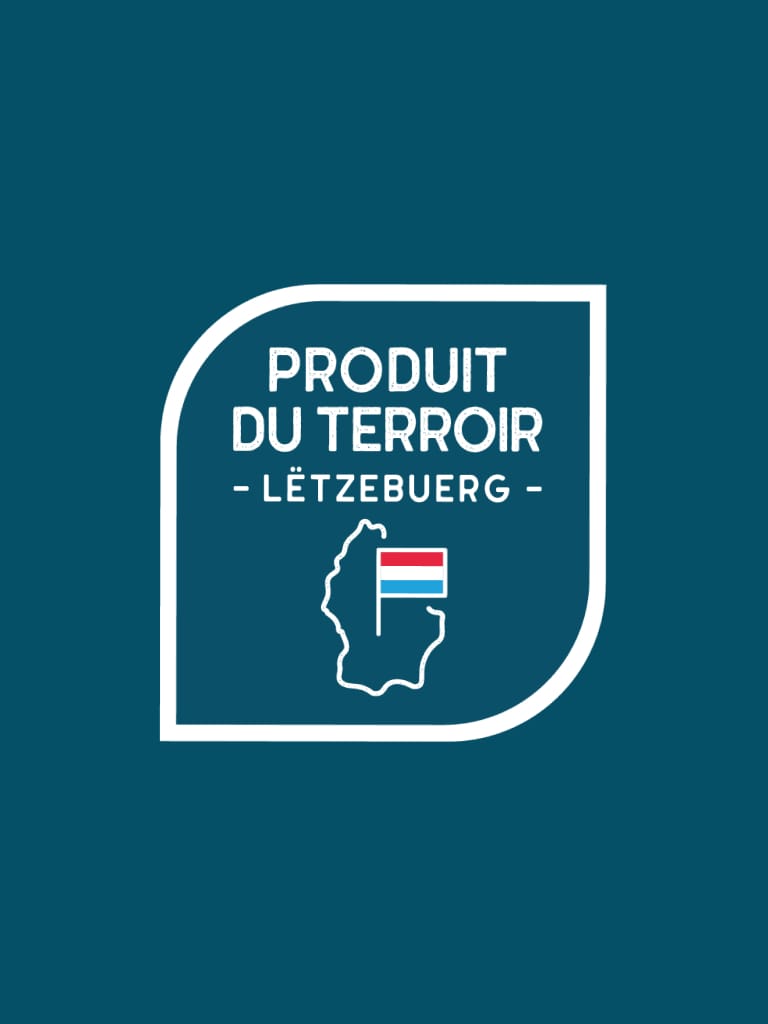 Insigne à contour blanc sur fond bleu avec le texte Produit du Terroir Lëtzebuerg. Sous le texte, un contour du Luxembourg contenant un petit drapeau luxembourgeois.